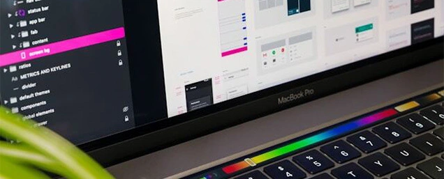 A MacBook Pro displaying a UI/UX design process with code, wireframes, and mockups.